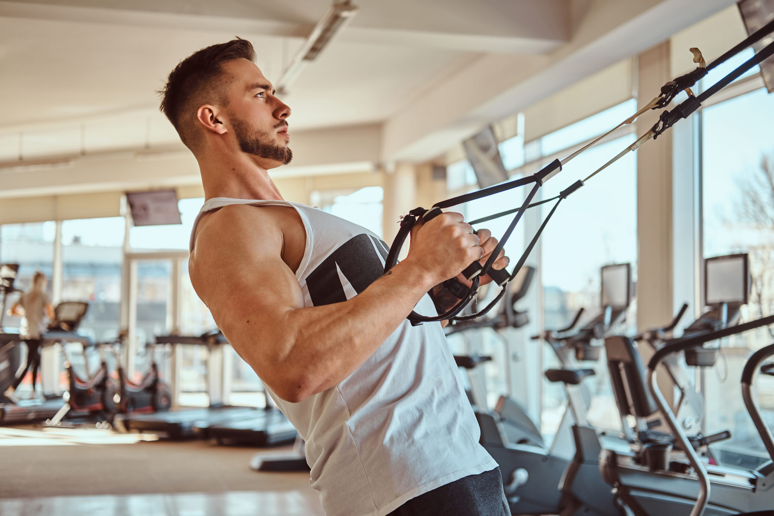 Powerful bodybuilder is doing exercises on training apparatus